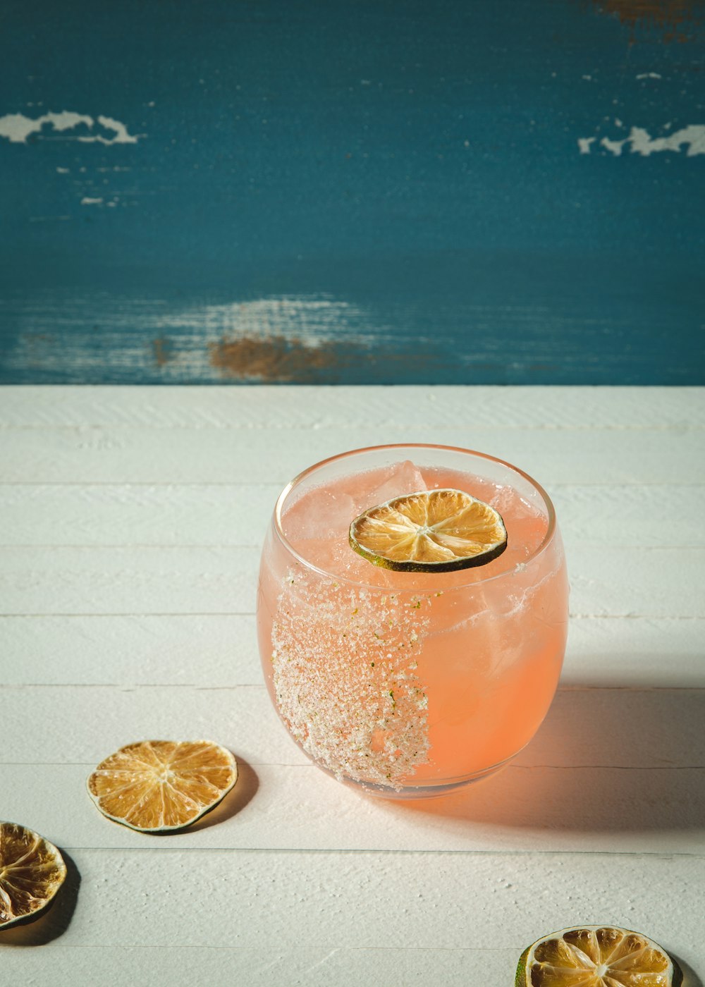 a glass filled with a drink next to sliced lemons