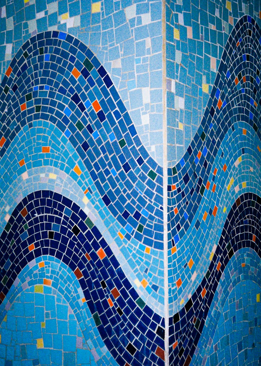 two images of a wall with blue and orange tiles