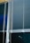 Horizontal blinds cover three large window panels. The blinds are partially closed, with several cords hanging down to adjust their position. The background outside the window is dark, suggesting it might be nighttime.