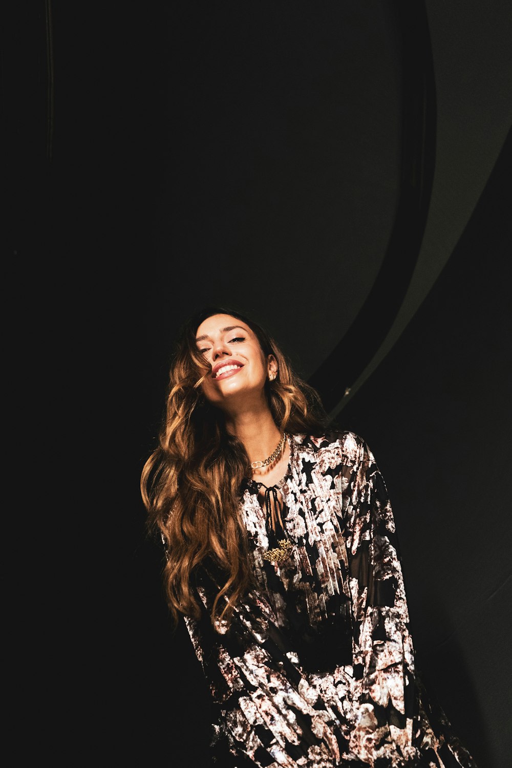 a woman sitting on a chair in front of a black wall