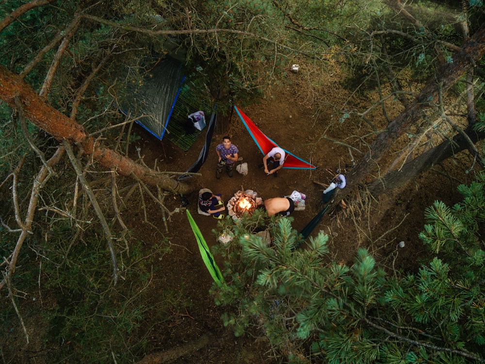 a group of people sitting around a campfire in the woods