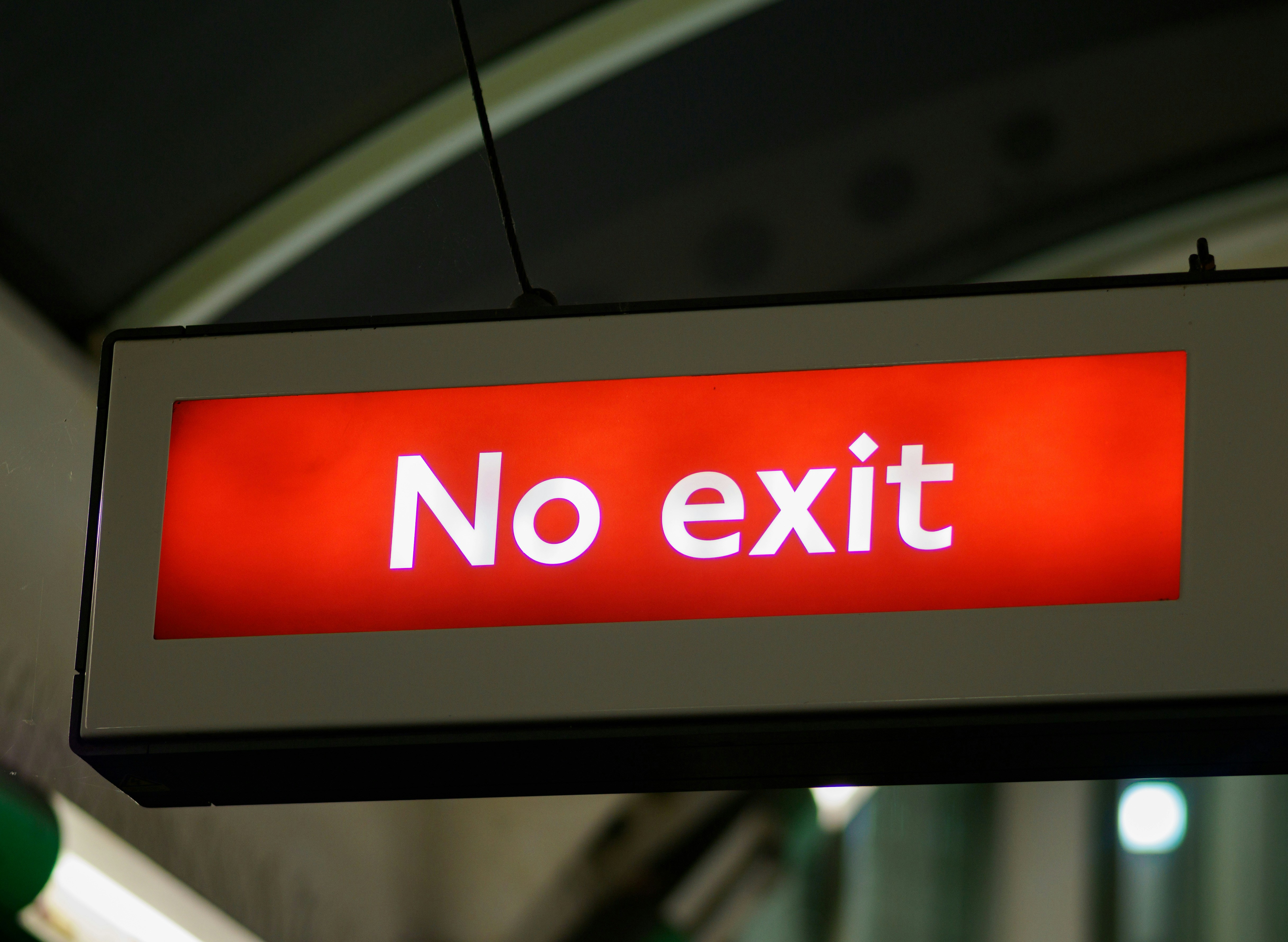 a red sign that says no exit hanging from a ceiling