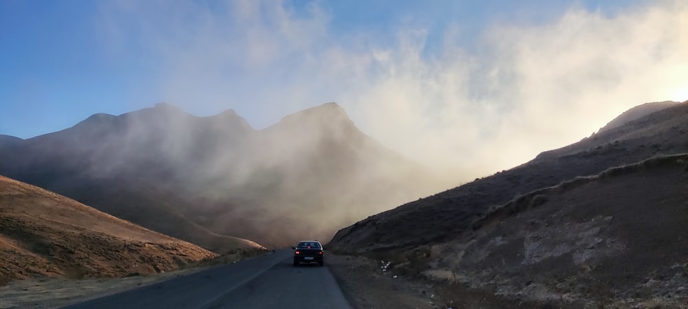 a car driving down a road with mountains in the background