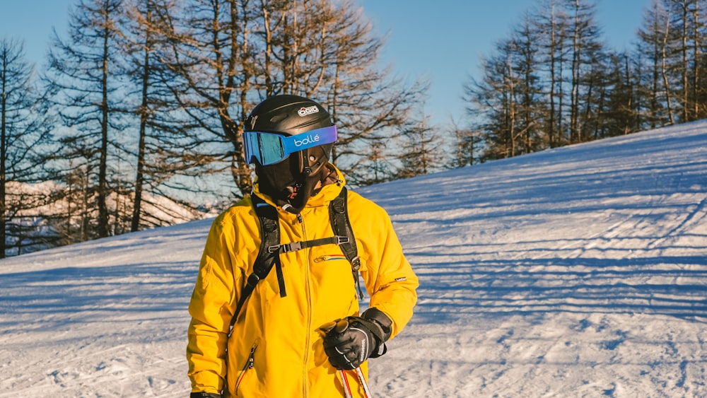 a man in a yellow jacket is standing in the snow