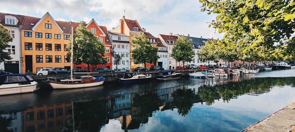 a row of boats sitting on top of a river next to tall buildings