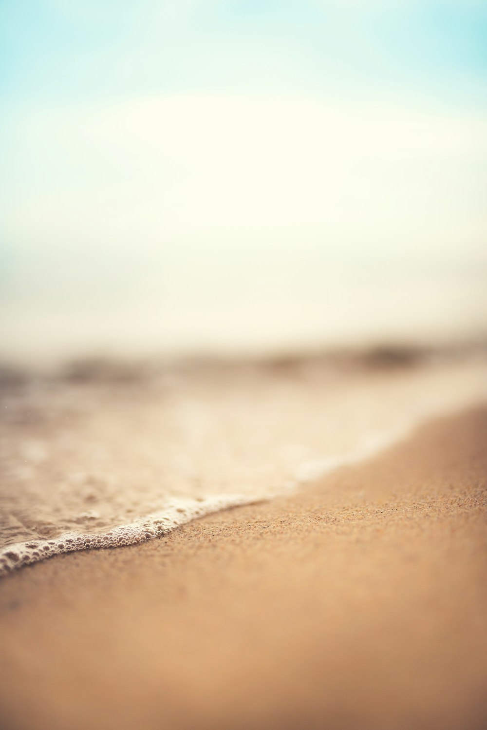 a blurry photo of a beach with a wave coming in