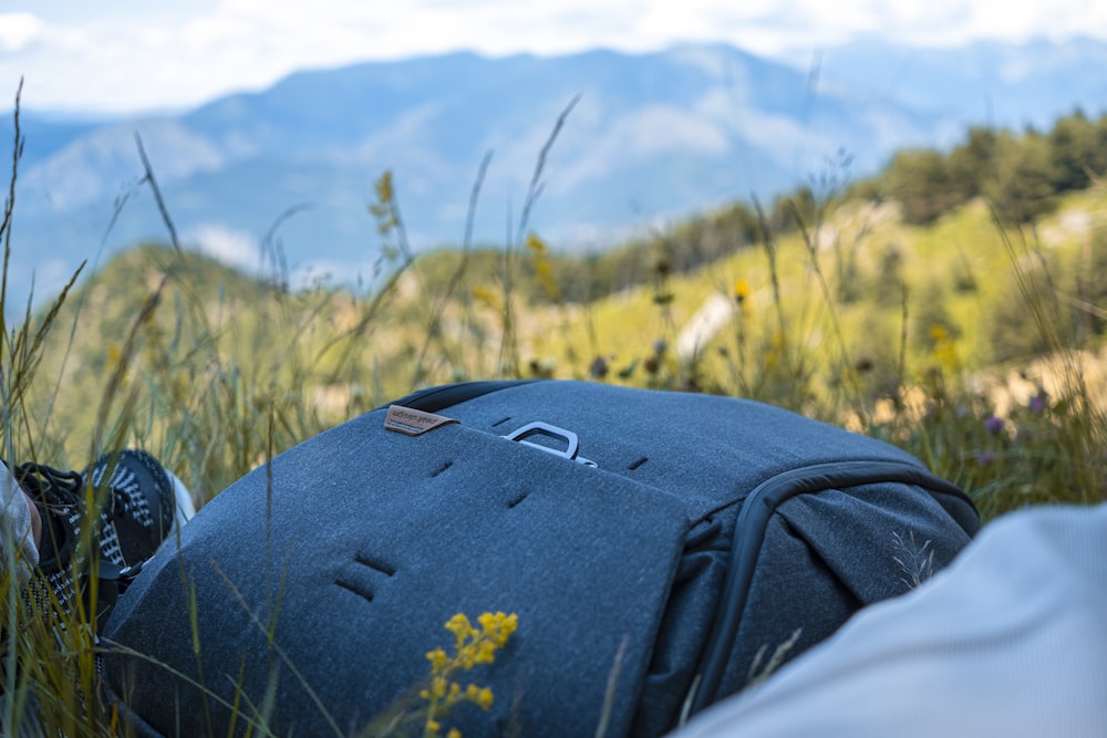 a person laying in the grass with a backpack on their back