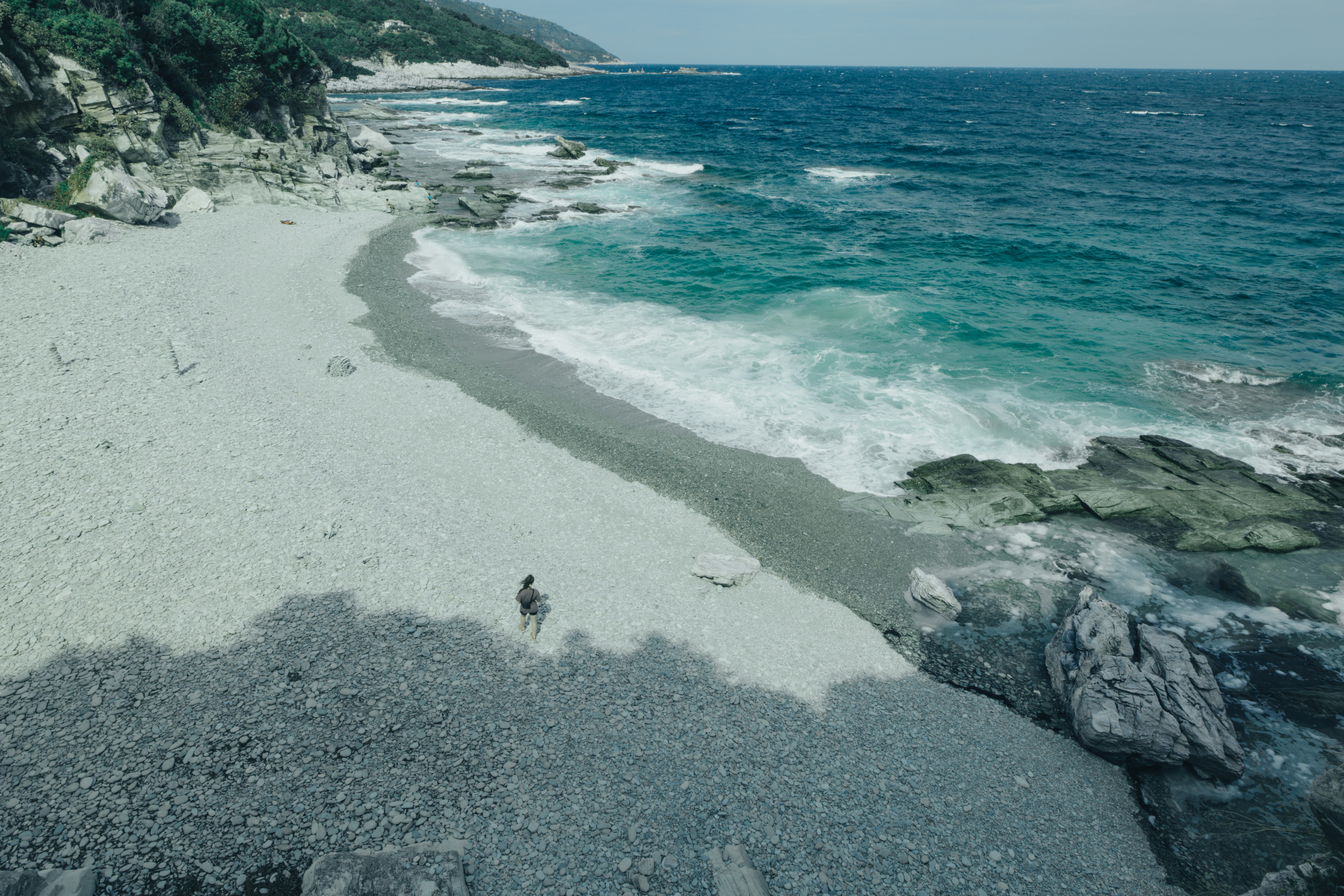 an aerial view of a beach with a person walking on it