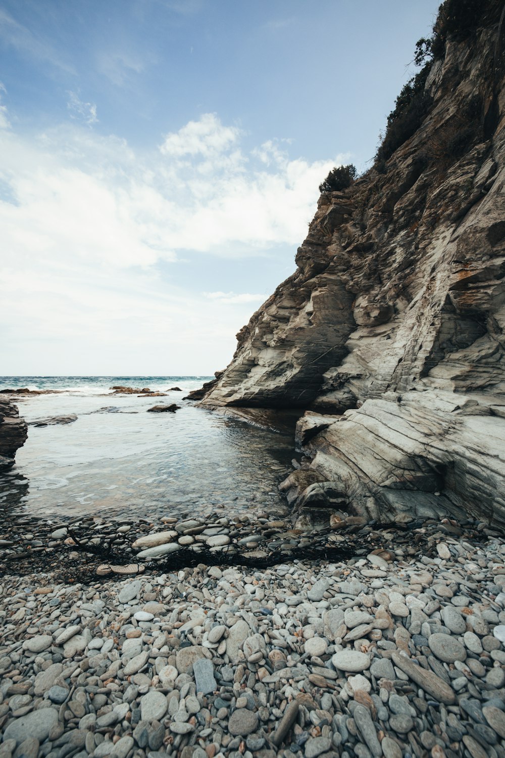 a rocky beach next to the ocean under a blue sky