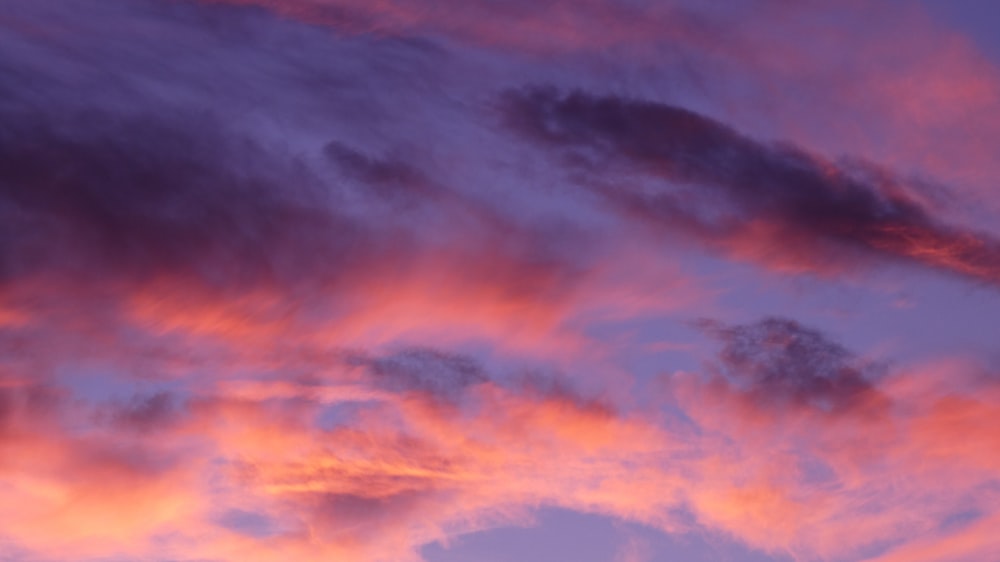 a plane flying in the sky at sunset