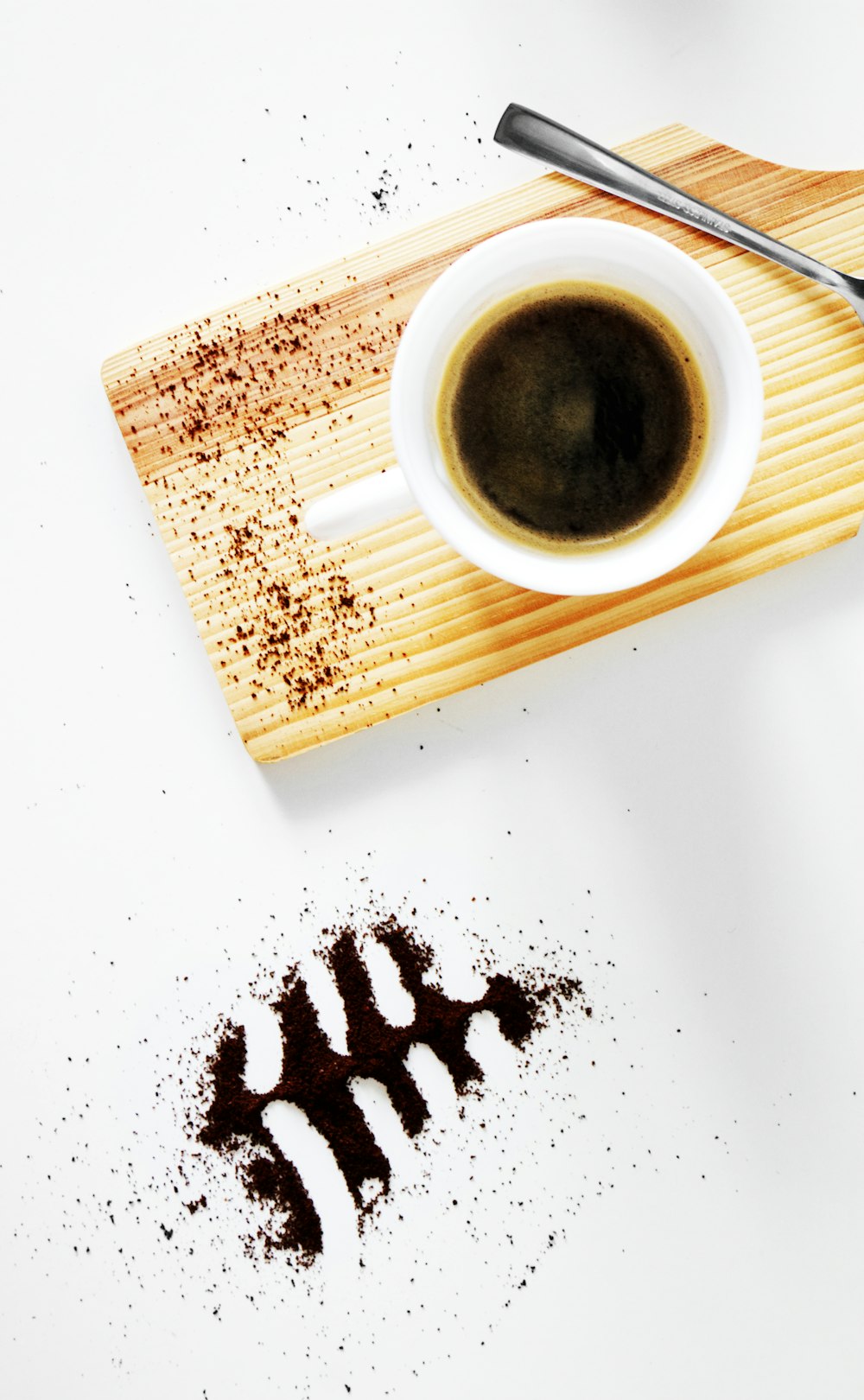 a cup of coffee with a spoon on a cutting board