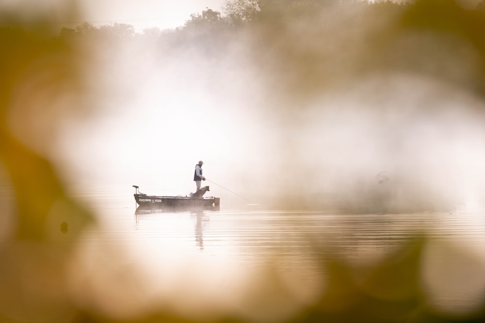 a man standing on a boat in the middle of a lake