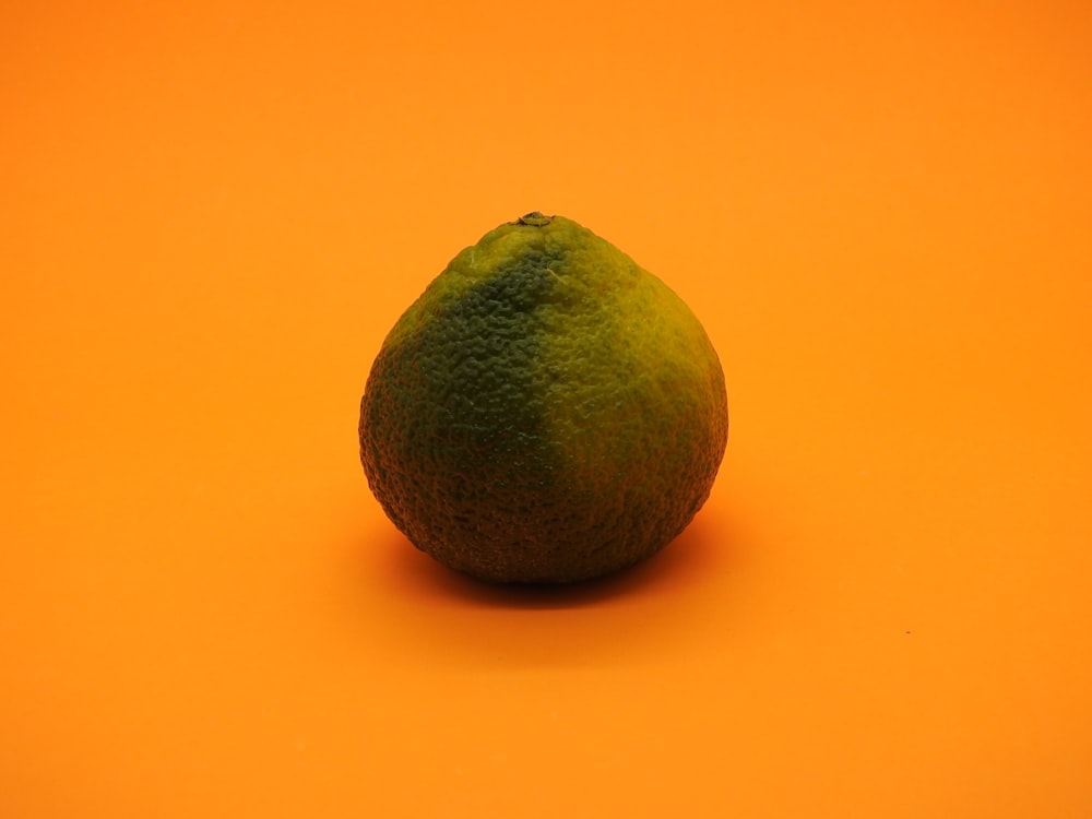 a lime sitting on an orange background