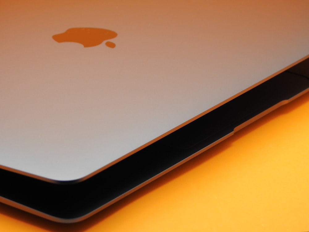 an apple laptop computer sitting on top of a yellow table