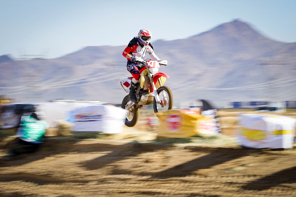 Dirt bike rider jumping on a desert race course with mountains behind