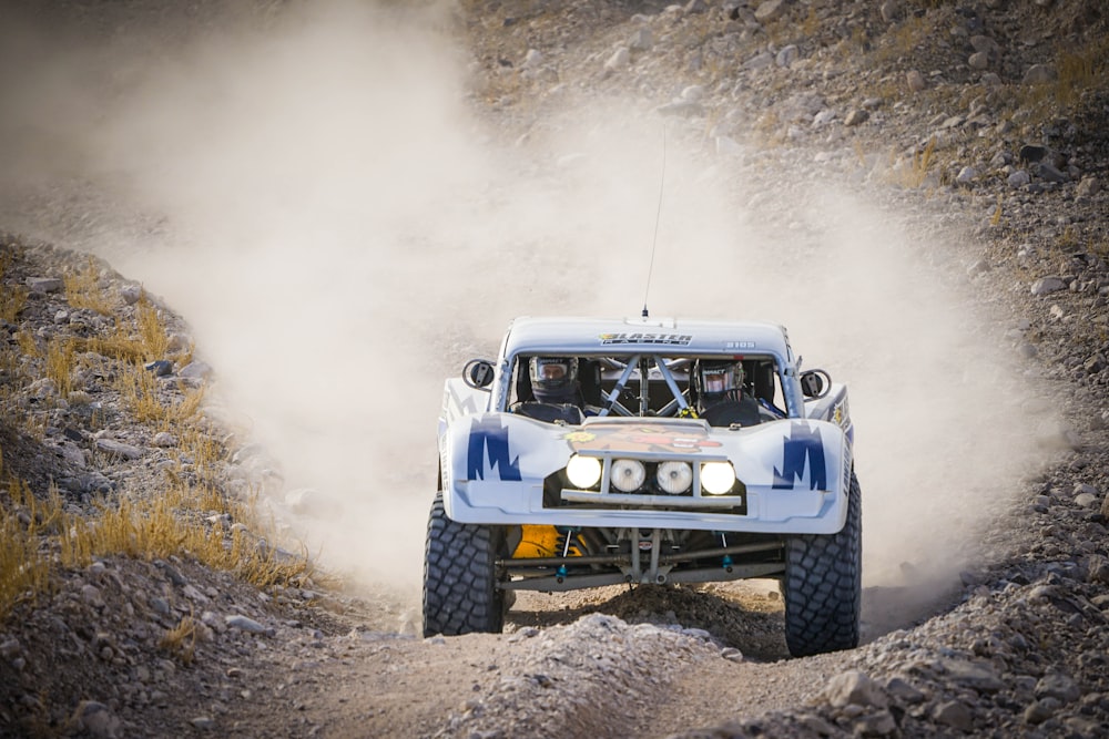 a blue and white truck driving down a dirt road