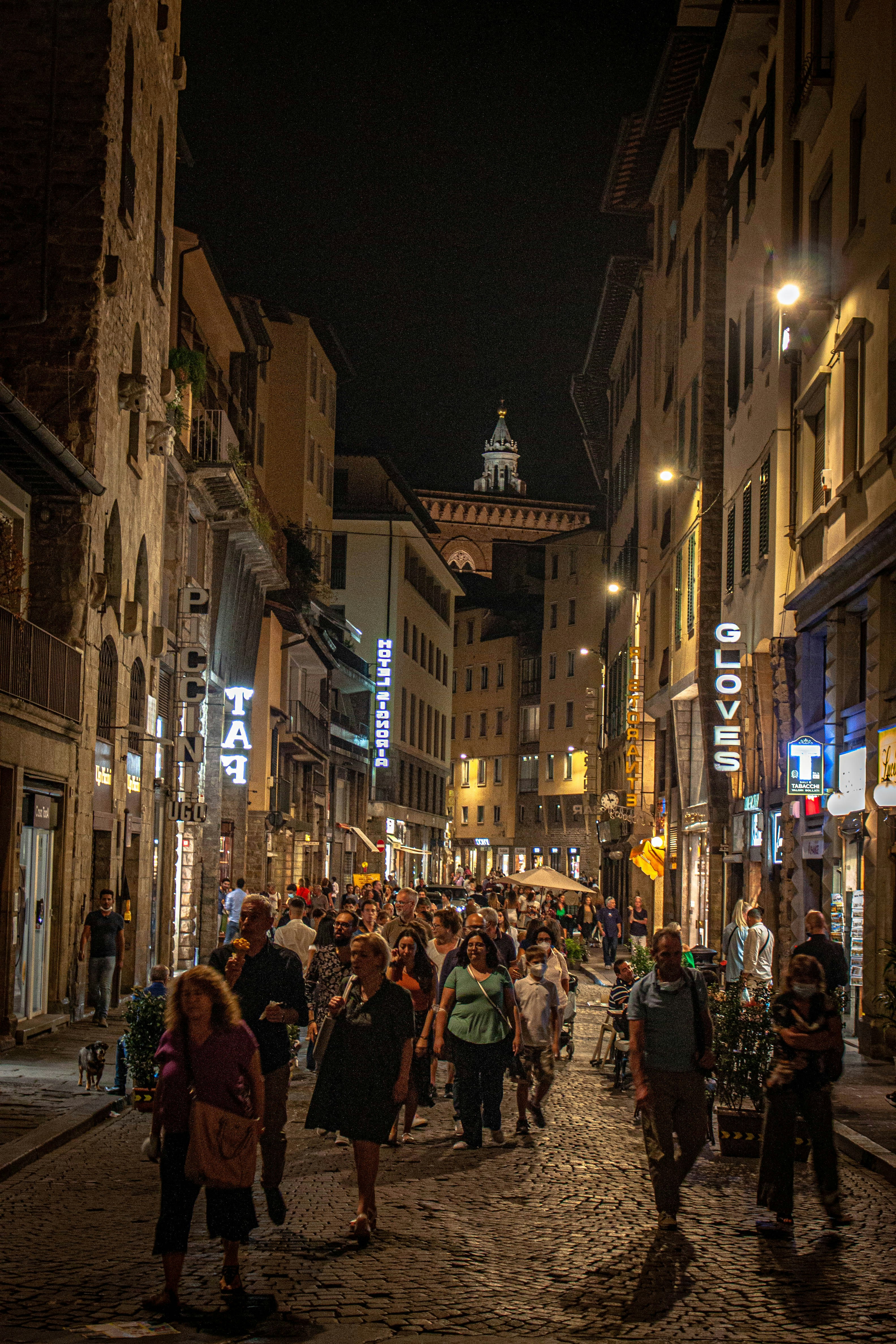 A group of people walking down a street next to tall buildings photo ...