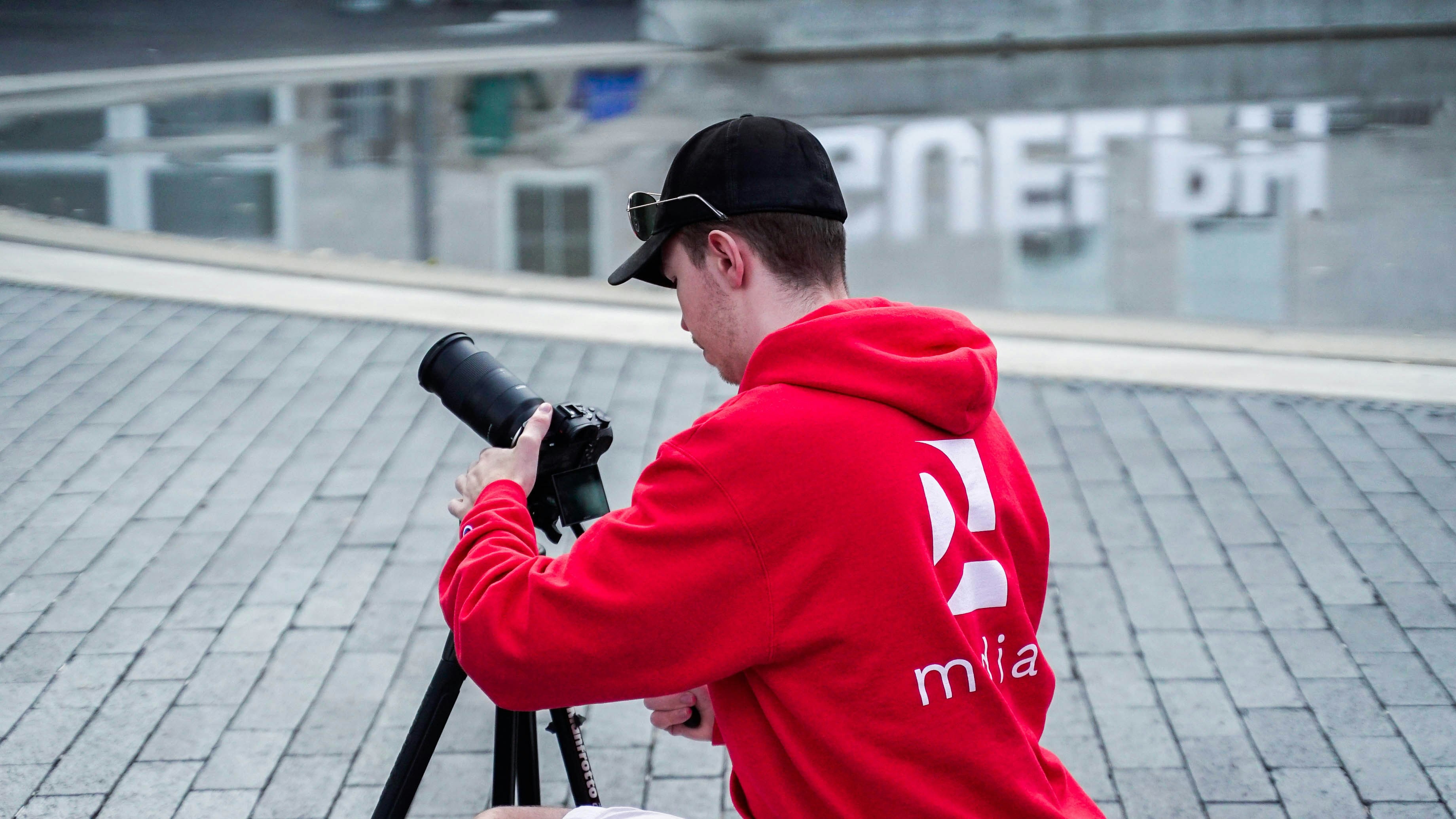 a man in a red hoodie taking a picture with a camera