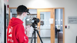 a man in a red hoodie is using a tripod