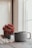 A beautifully crafted ceramic mug with a glossy finish, placed on a wooden table next to a small plant.