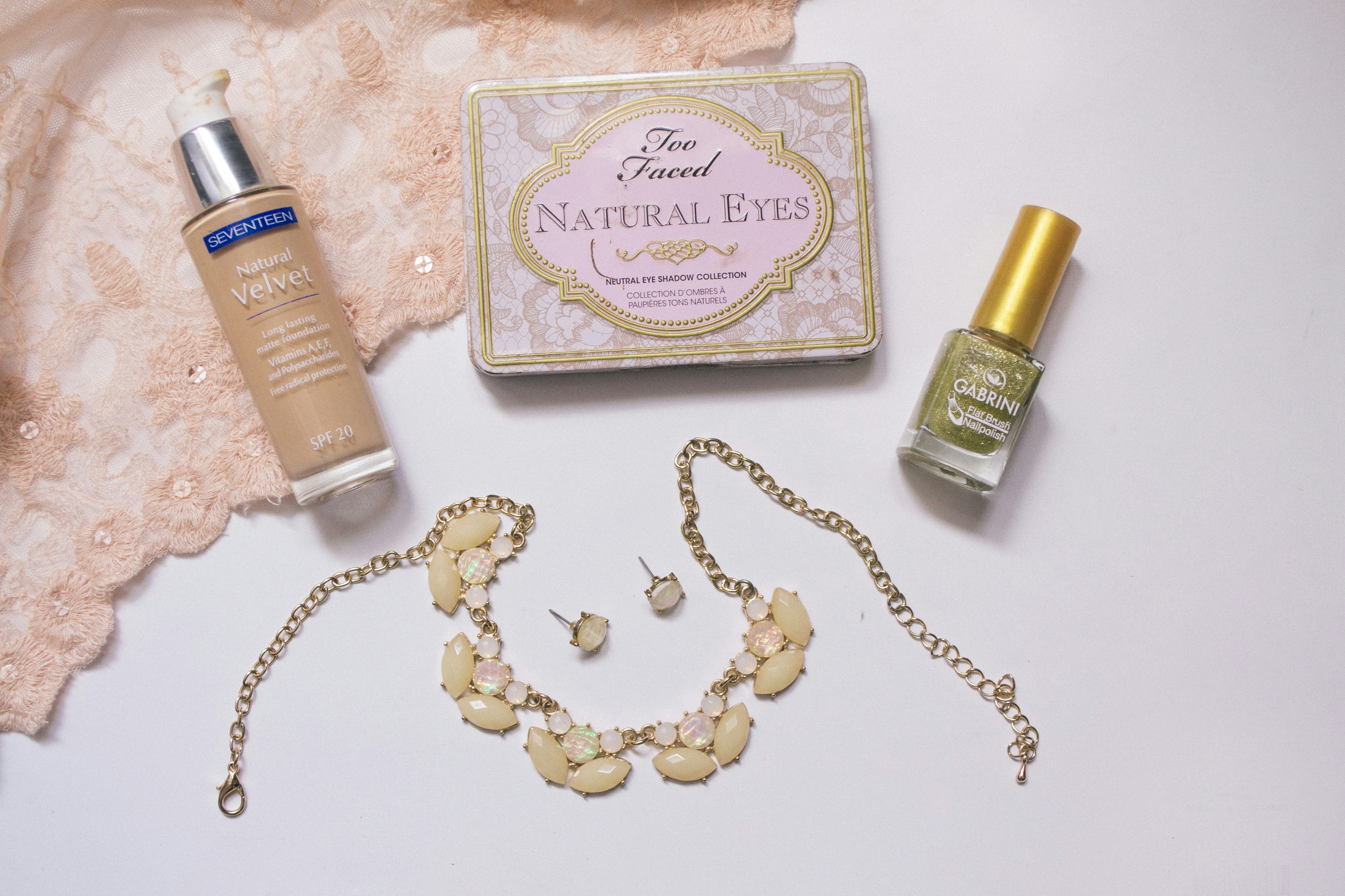 a white table topped with cosmetics and a necklace