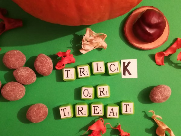 Trick or treat letter tiles and Halloween candy on a table, a reminder to bring a candy bag to the free Monster Mash and Movie Bash