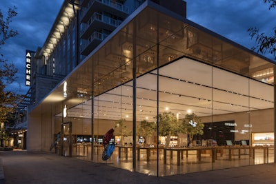 a large glass building with a tree in front of it