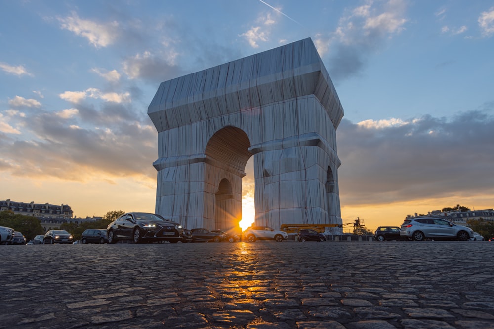 the sun is setting behind a monument in a parking lot