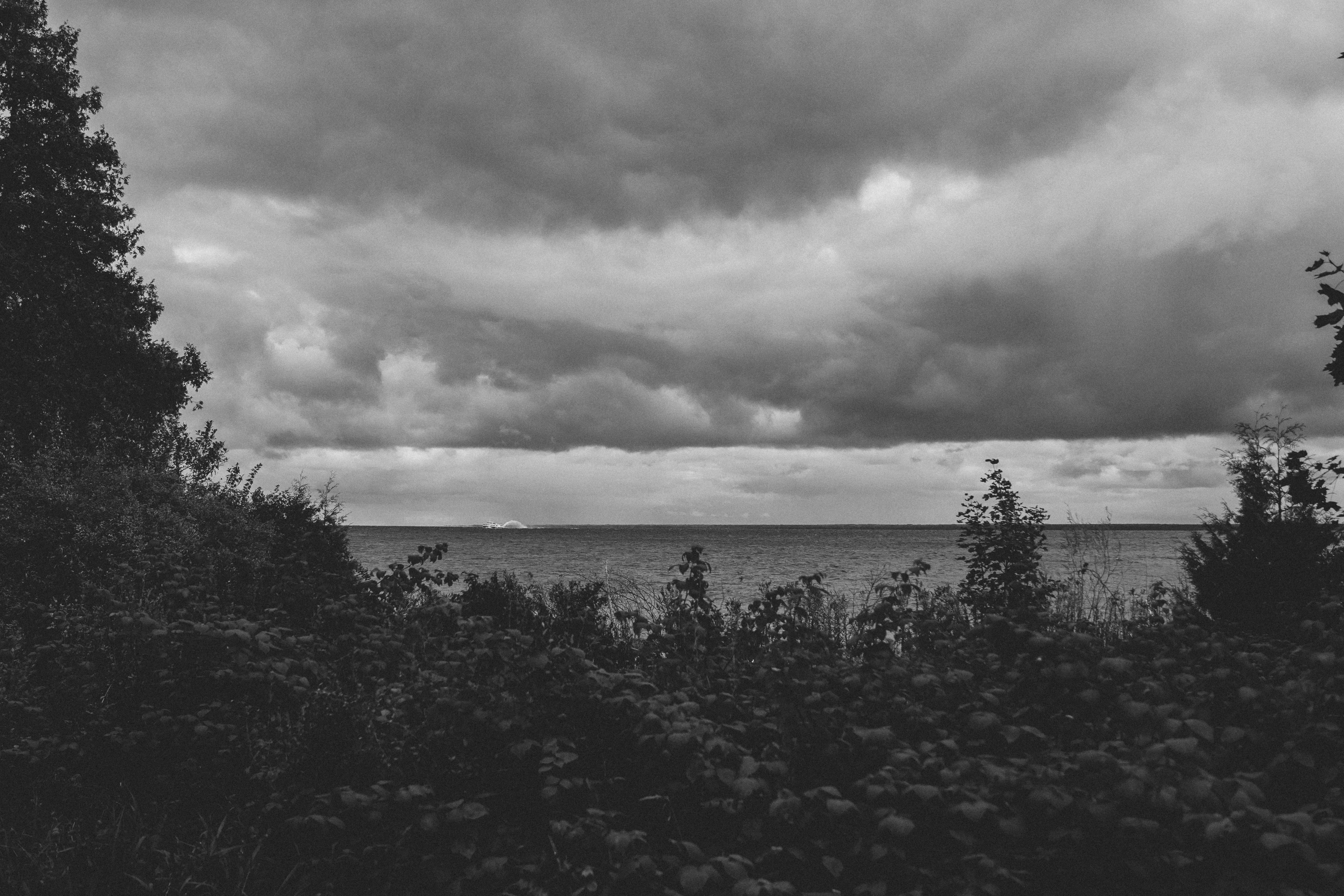 Viking warrior in a longship looking toward a distant horizon with dramatic cloudy skies