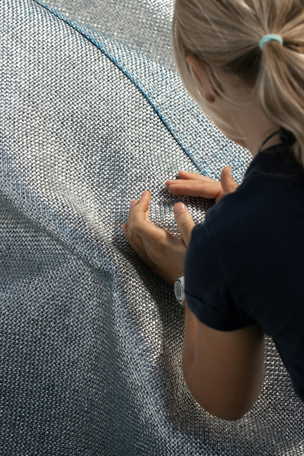 a woman sitting on the ground working on a piece of fabric