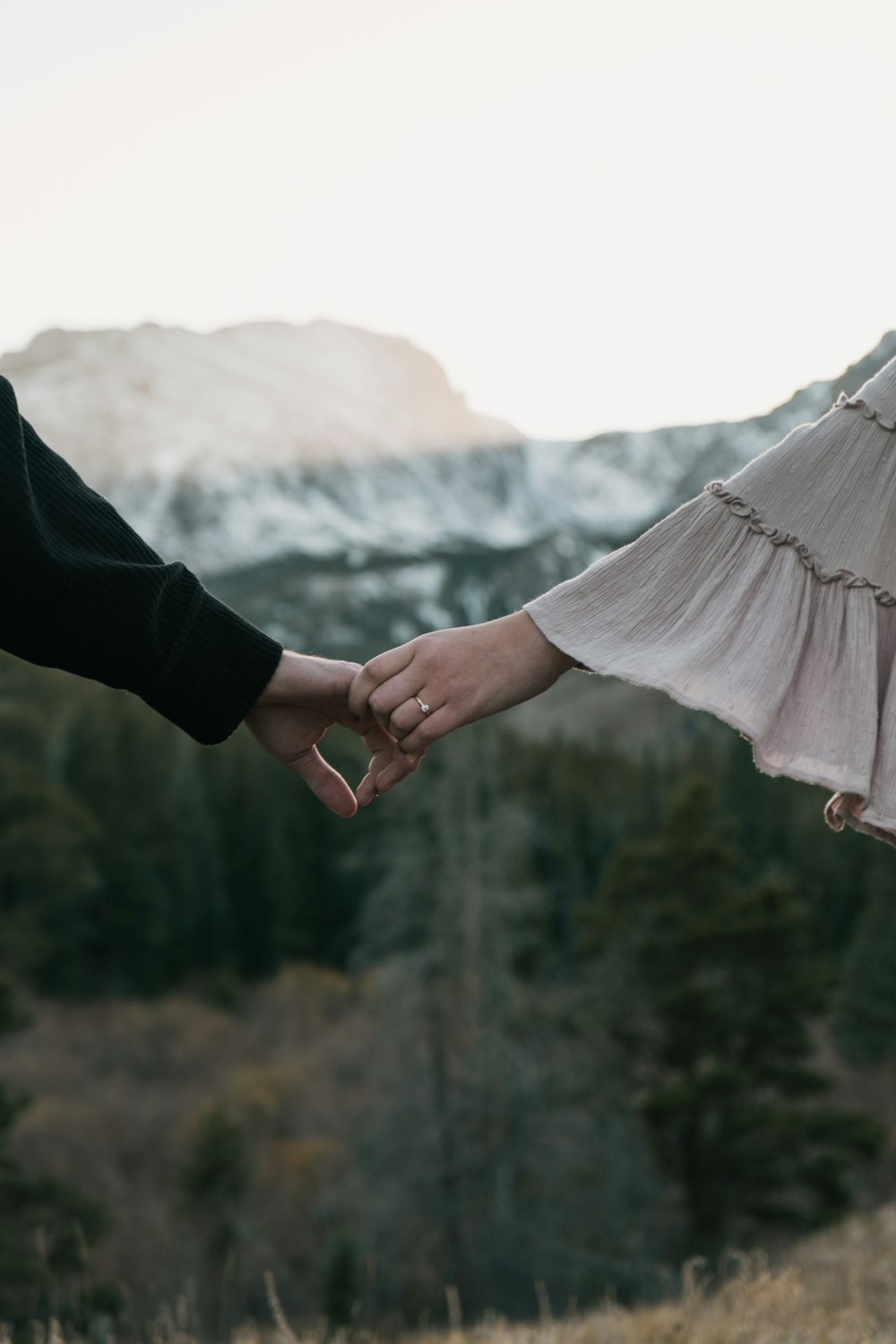 two people holding hands in front of a mountain