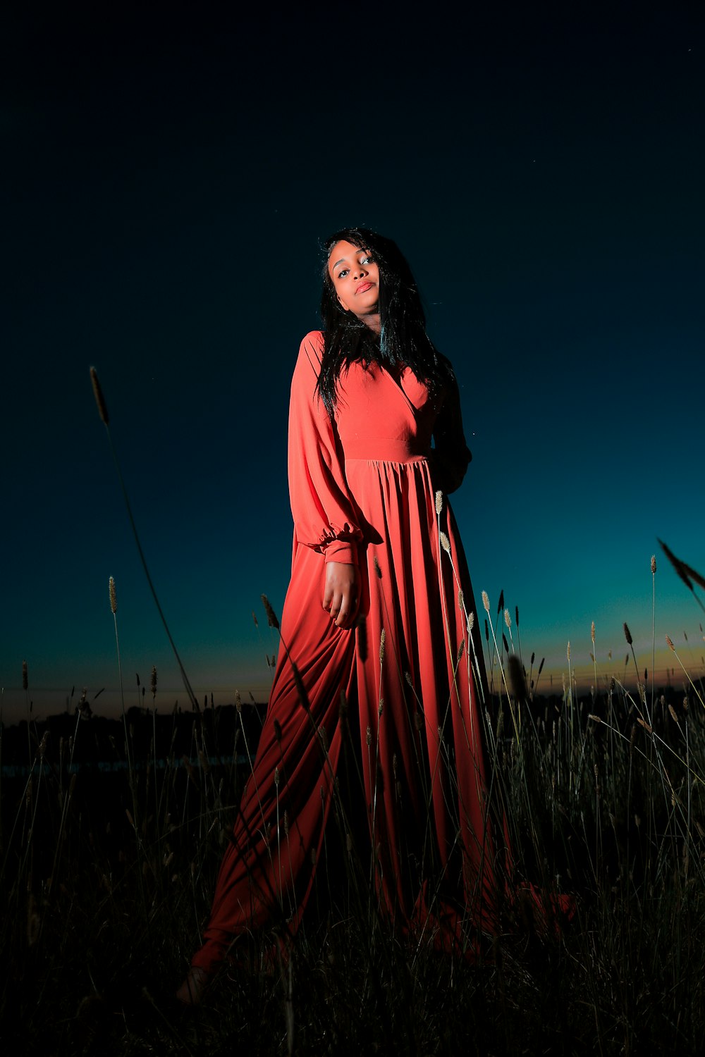 a woman in a red dress standing in tall grass