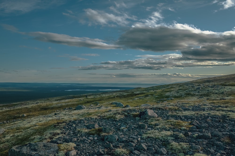 a hill with rocks and grass under a cloudy sky