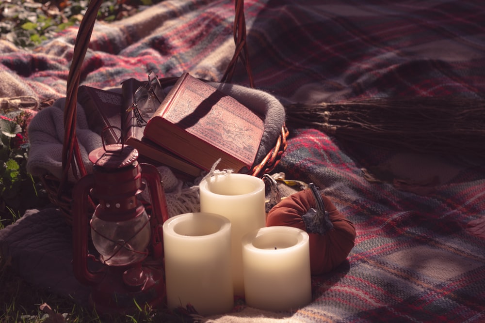 a plaid blanket with candles and a book on it