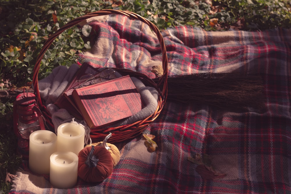 a basket of books and candles on a blanket