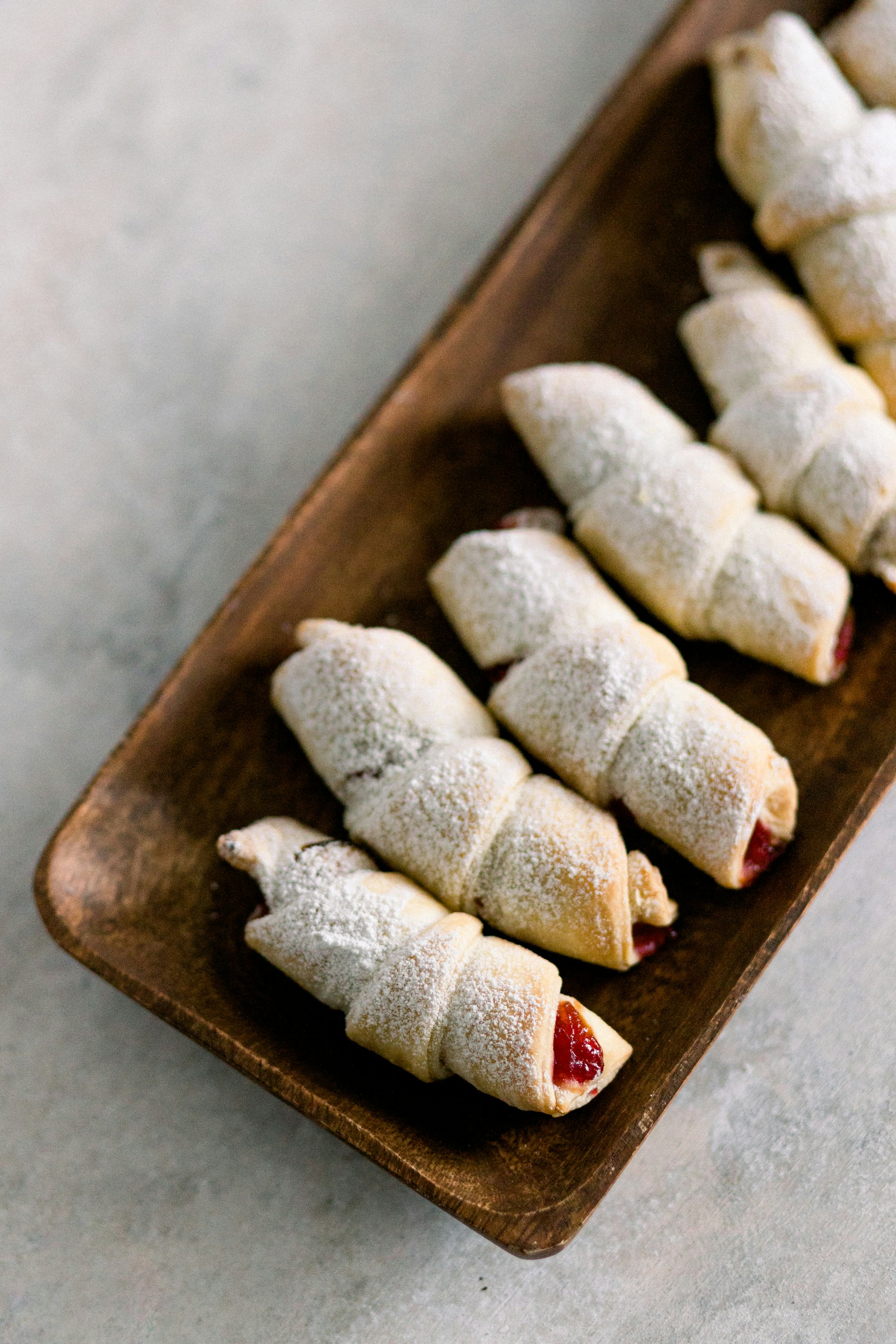 a wooden plate topped with pastries covered in powdered sugar