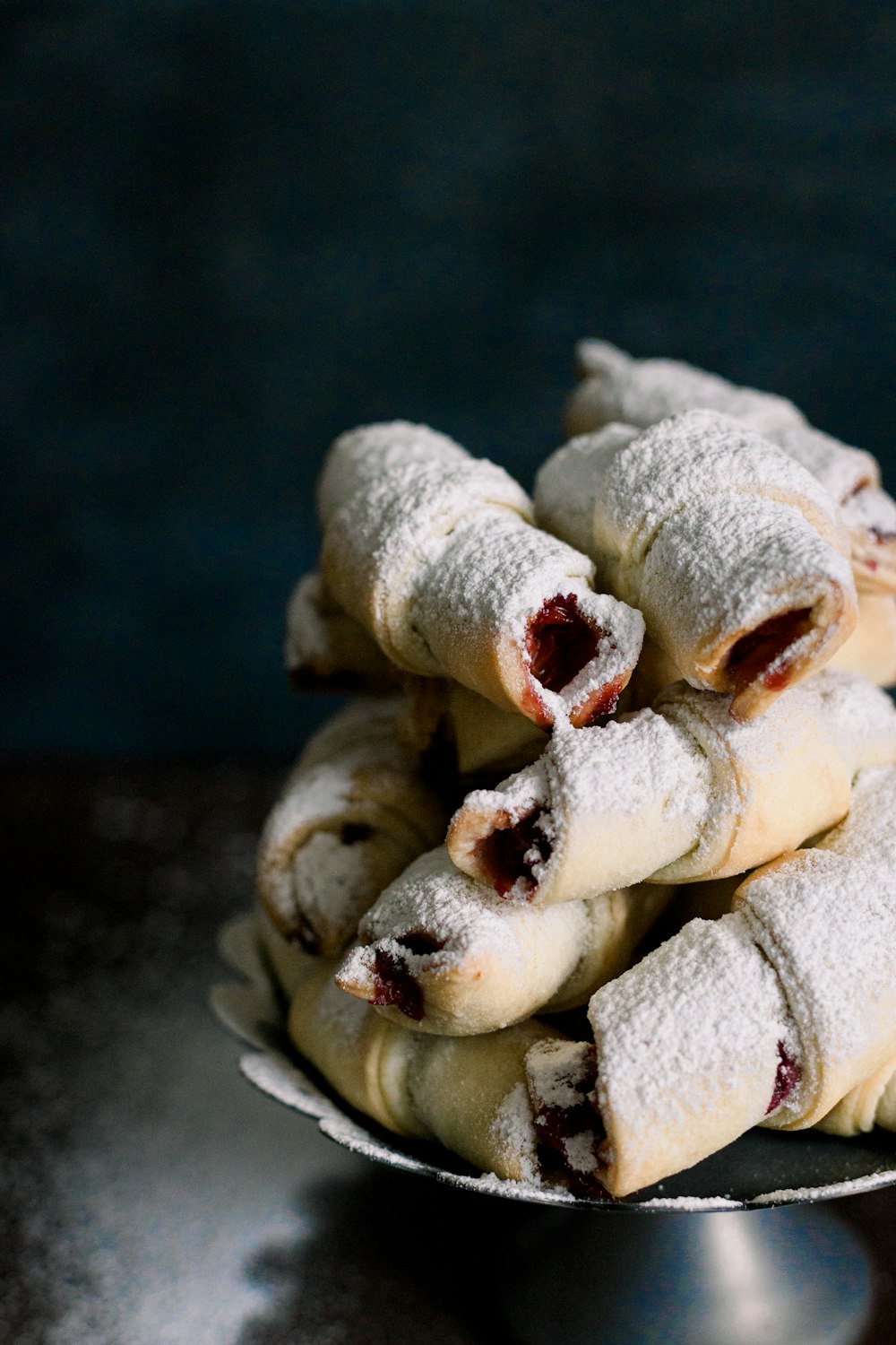 a metal bowl filled with powdered sugar covered pastries