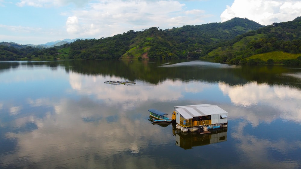 a boat floating on top of a lake next to a lush green hillside