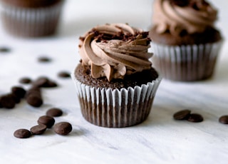 three chocolate cupcakes with chocolate frosting and chocolate chips