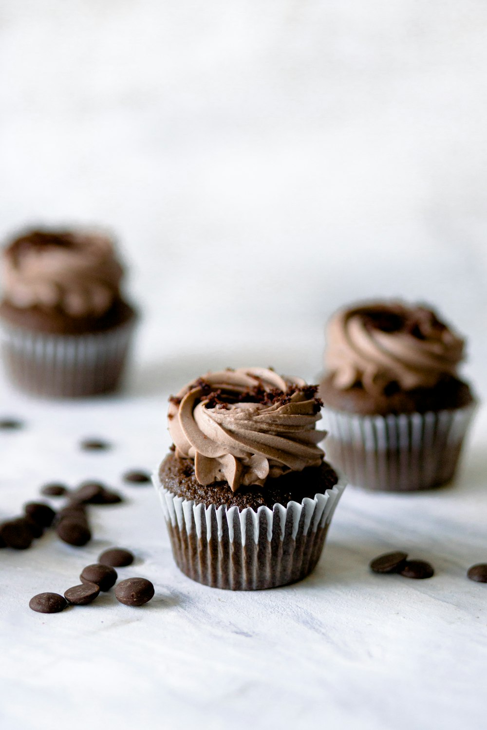 three chocolate cupcakes with chocolate frosting and chocolate chips