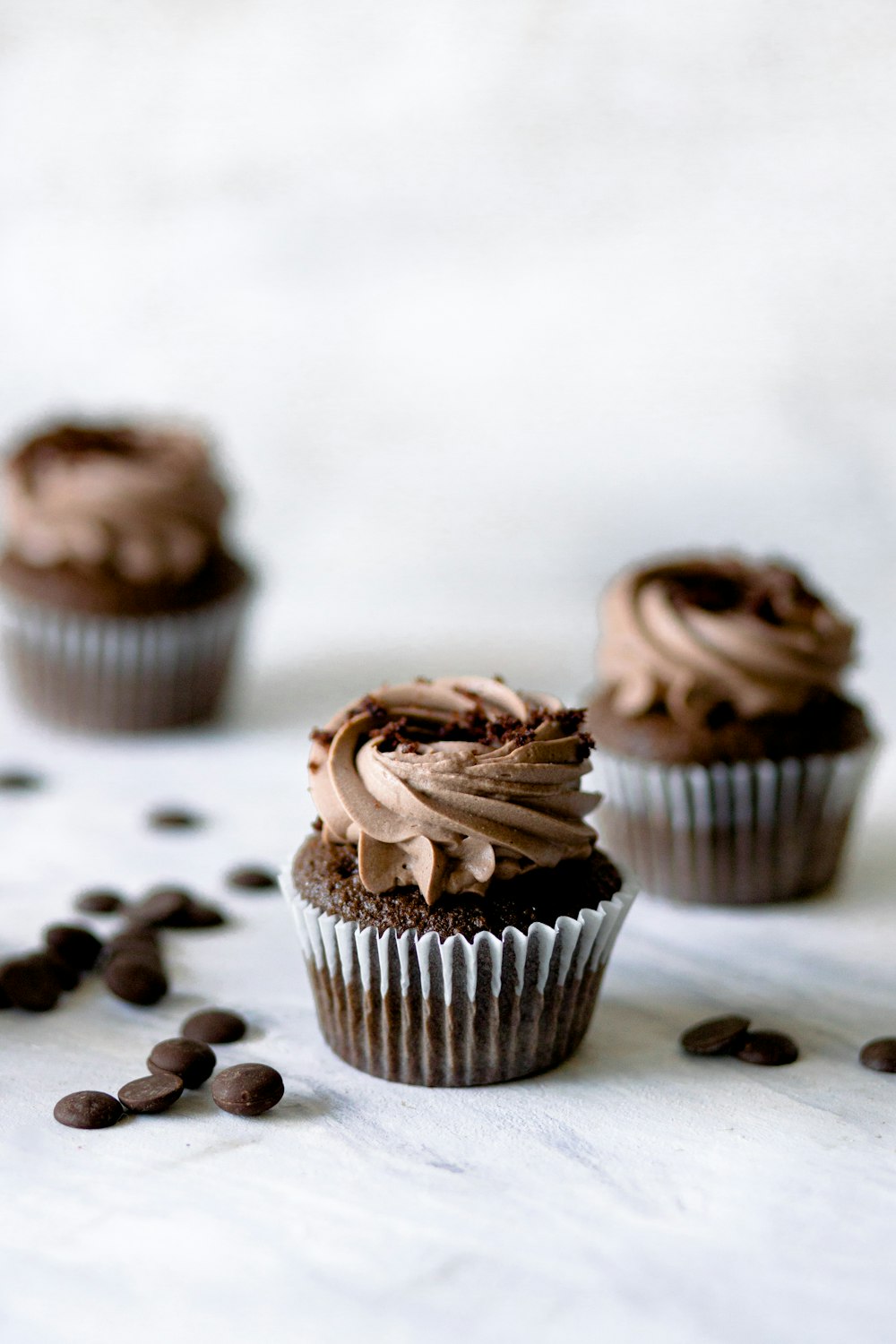 Tres cupcakes de chocolate con glaseado de chocolate y chispas de chocolate