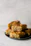 Close-up of a golden, flaky baklava piece with visible nuts and syrup glistening on top.