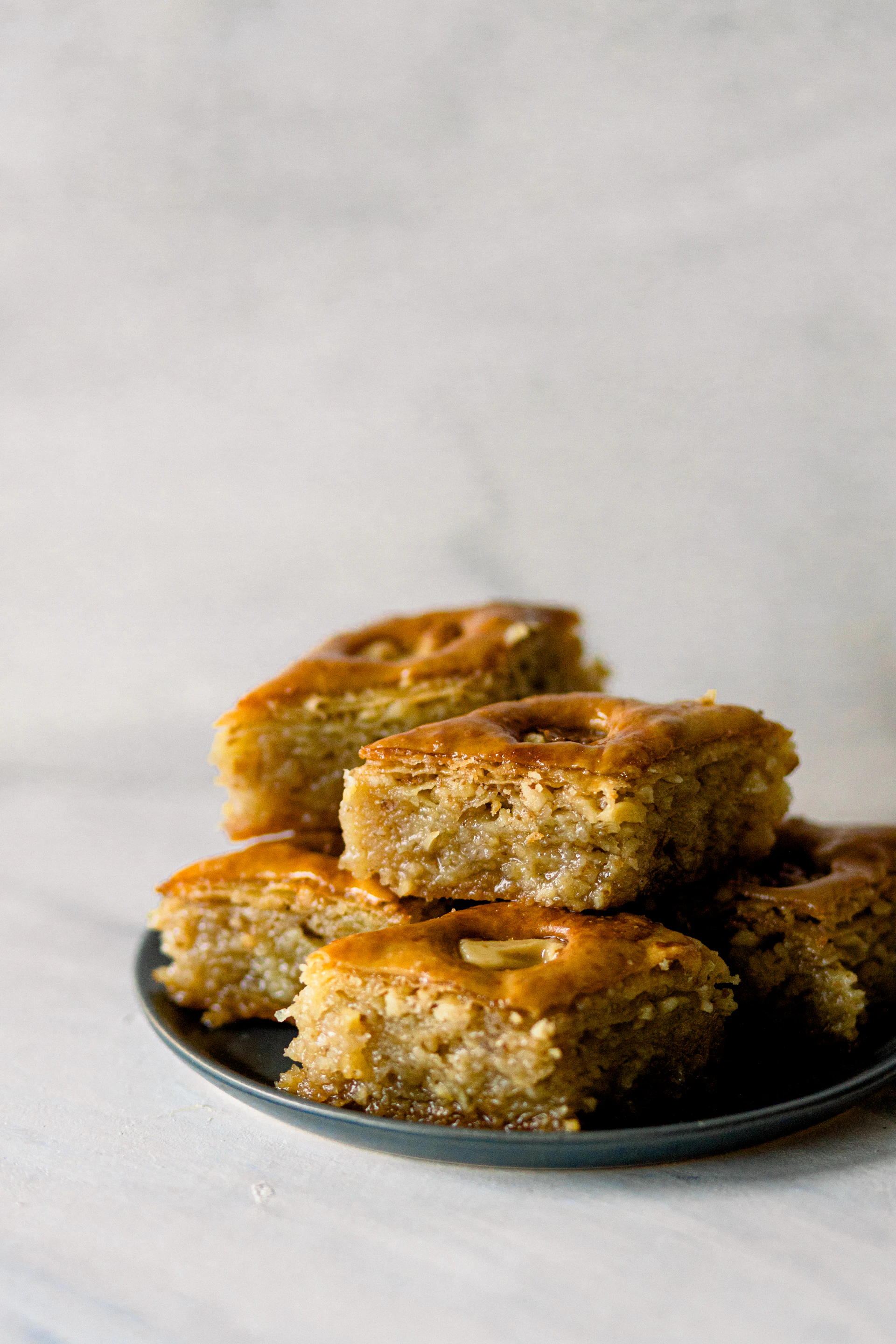A close-up of a golden, flaky baklava glistening with honey, arranged on an ancient Egyptian-style ceramic plate.