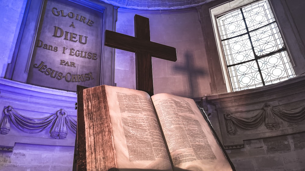 an open book sitting on top of a table next to a cross