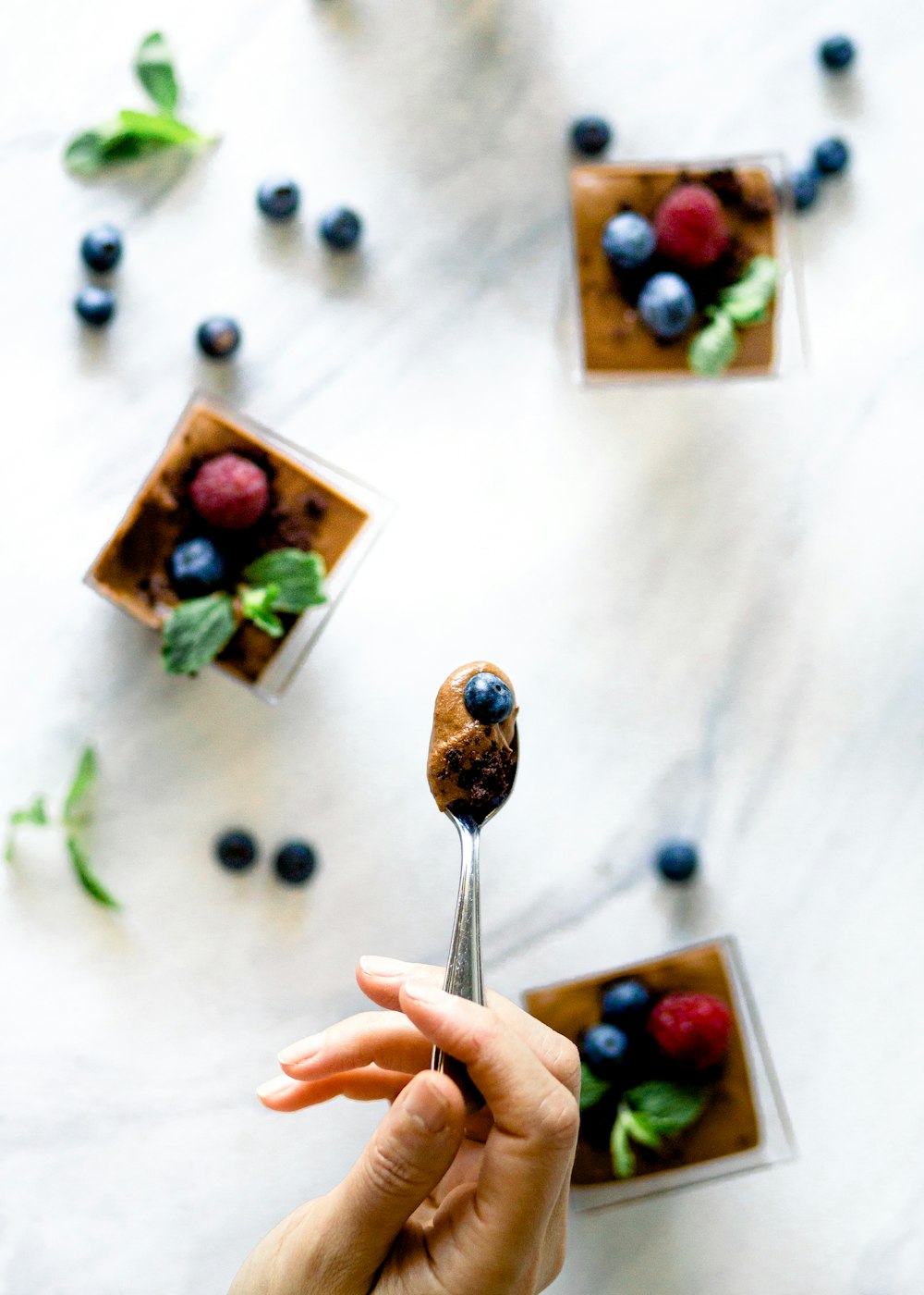 a person holding a spoon with a dessert on it