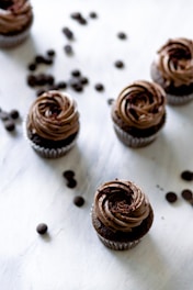 a table topped with chocolate cupcakes and coffee beans
