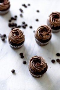 a table topped with chocolate cupcakes and coffee beans