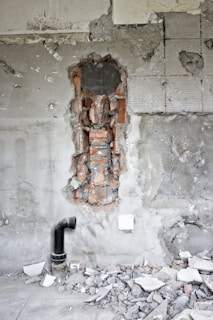 a fire hydrant sitting in front of a wall with a hole in it