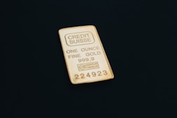 a gold bar one ounce sitting on top of a black surface