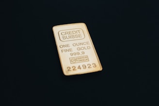 a gold bar one ounce sitting on top of a black surface